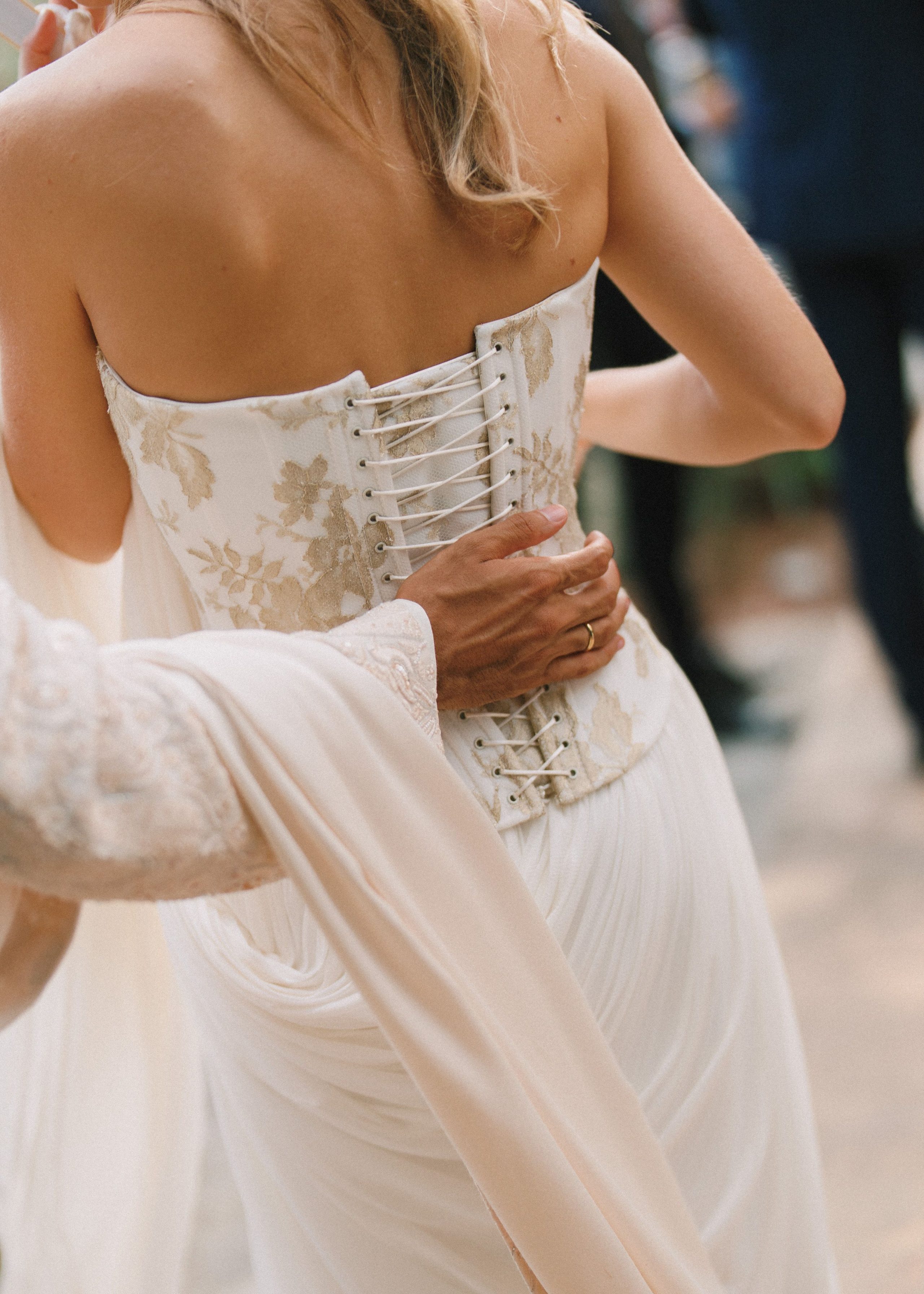 An embrace and the delicate detail of a bridal corset.