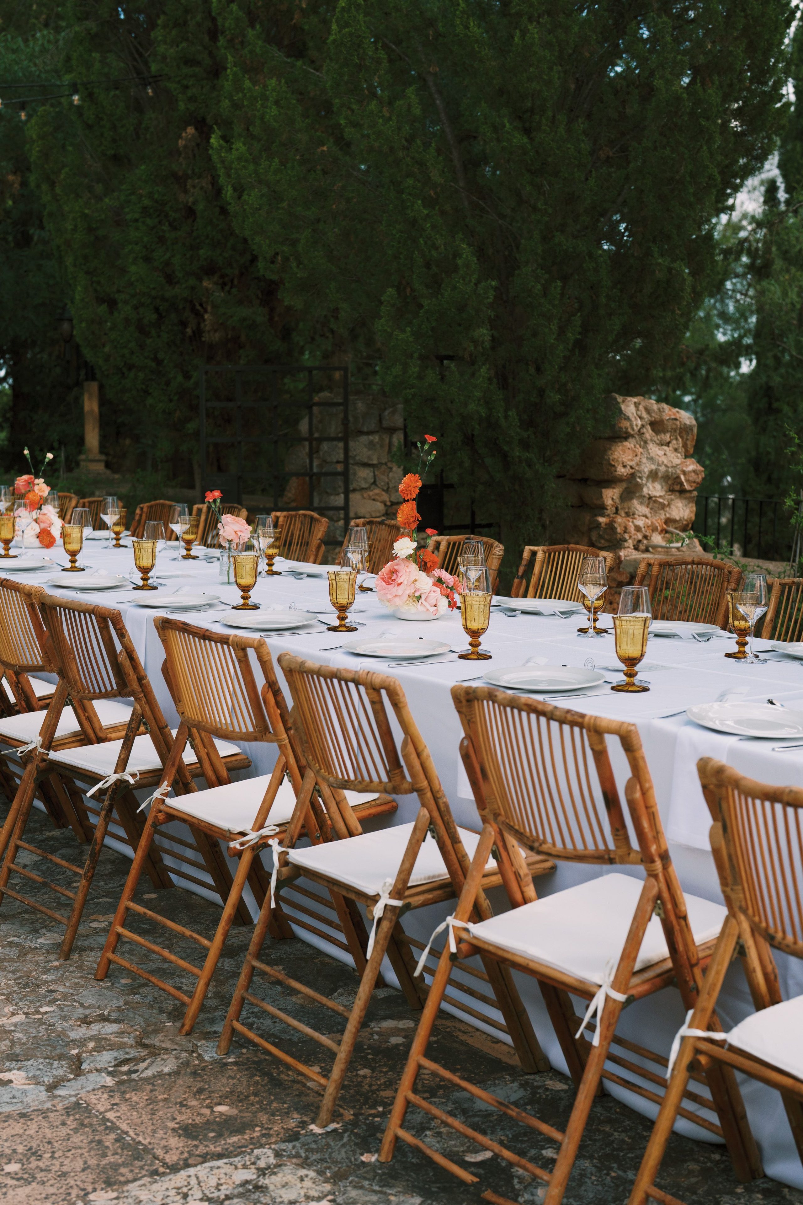 A long table set for an outdoor wedding meal.