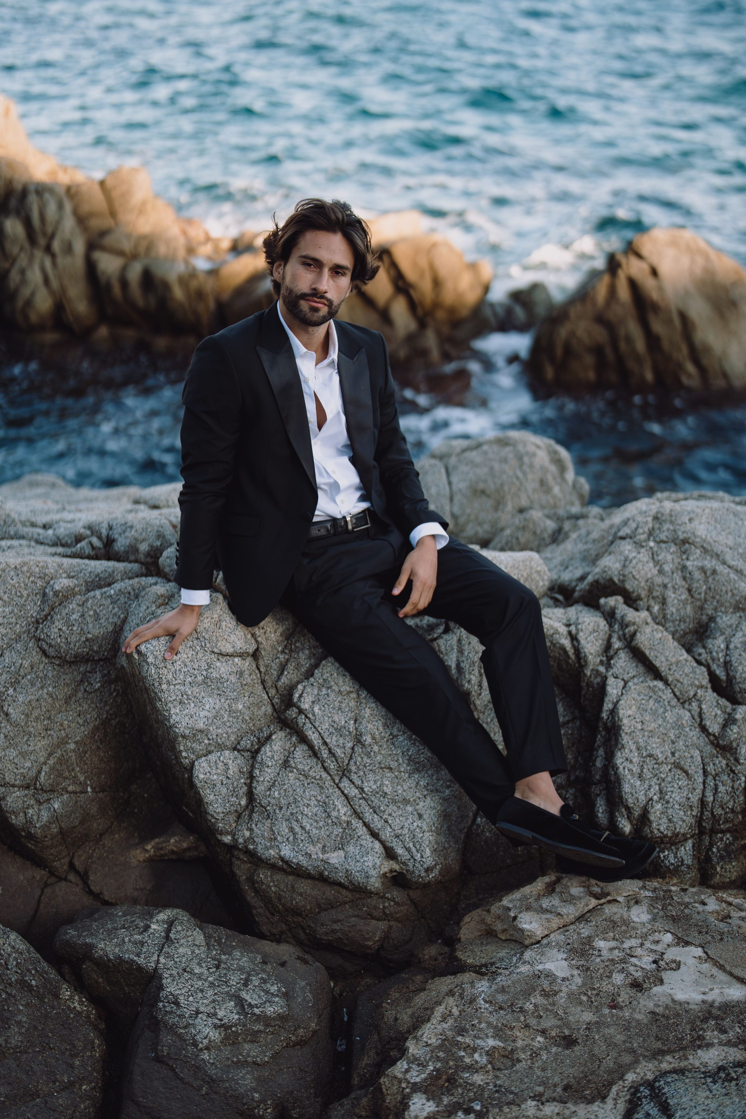 A relaxed groom's portrait beside the sea.