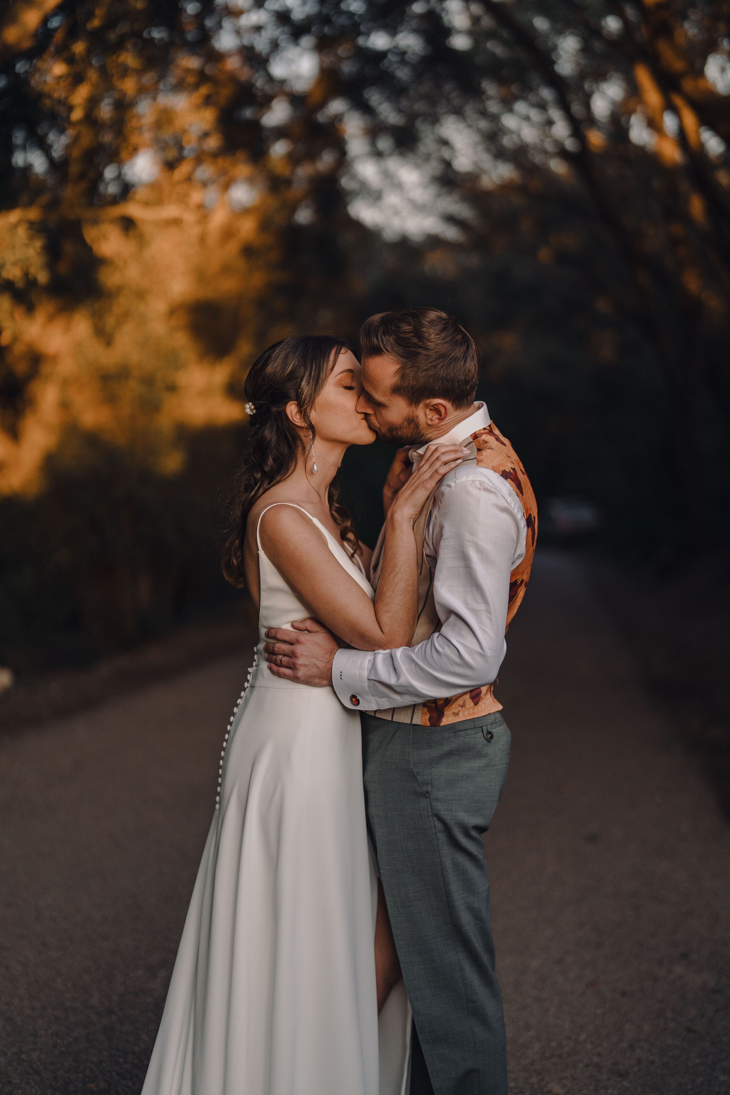 A kiss beneath the trees in the warm evening light.