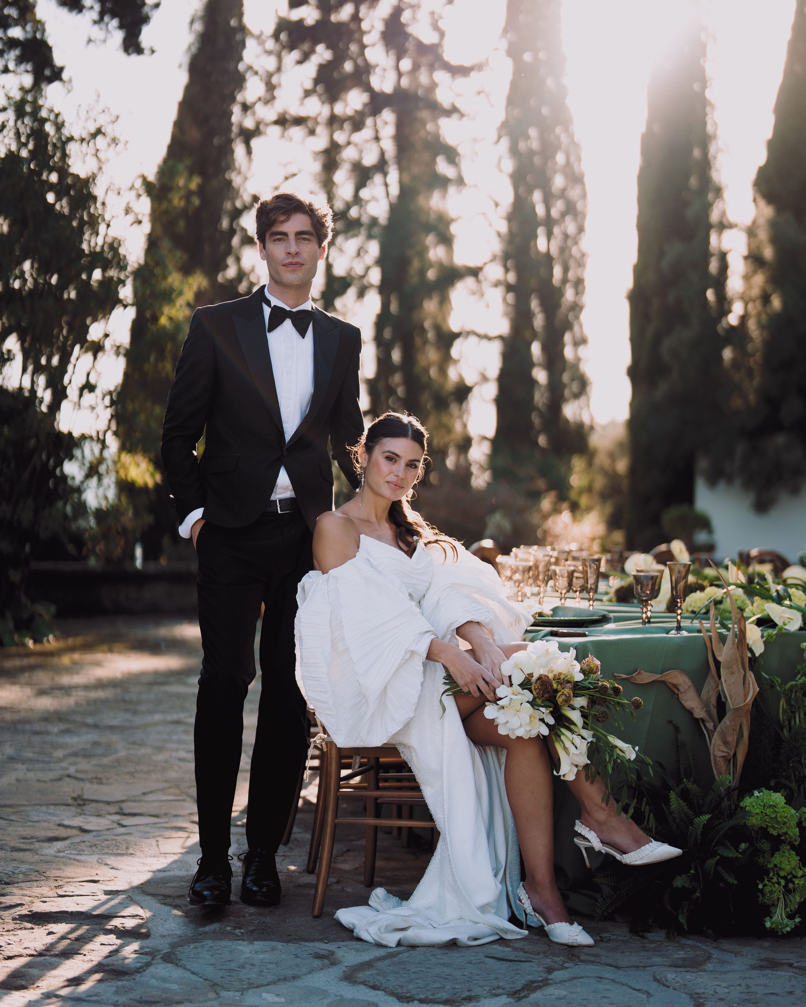A wedding portrait beside a table set among the trees.