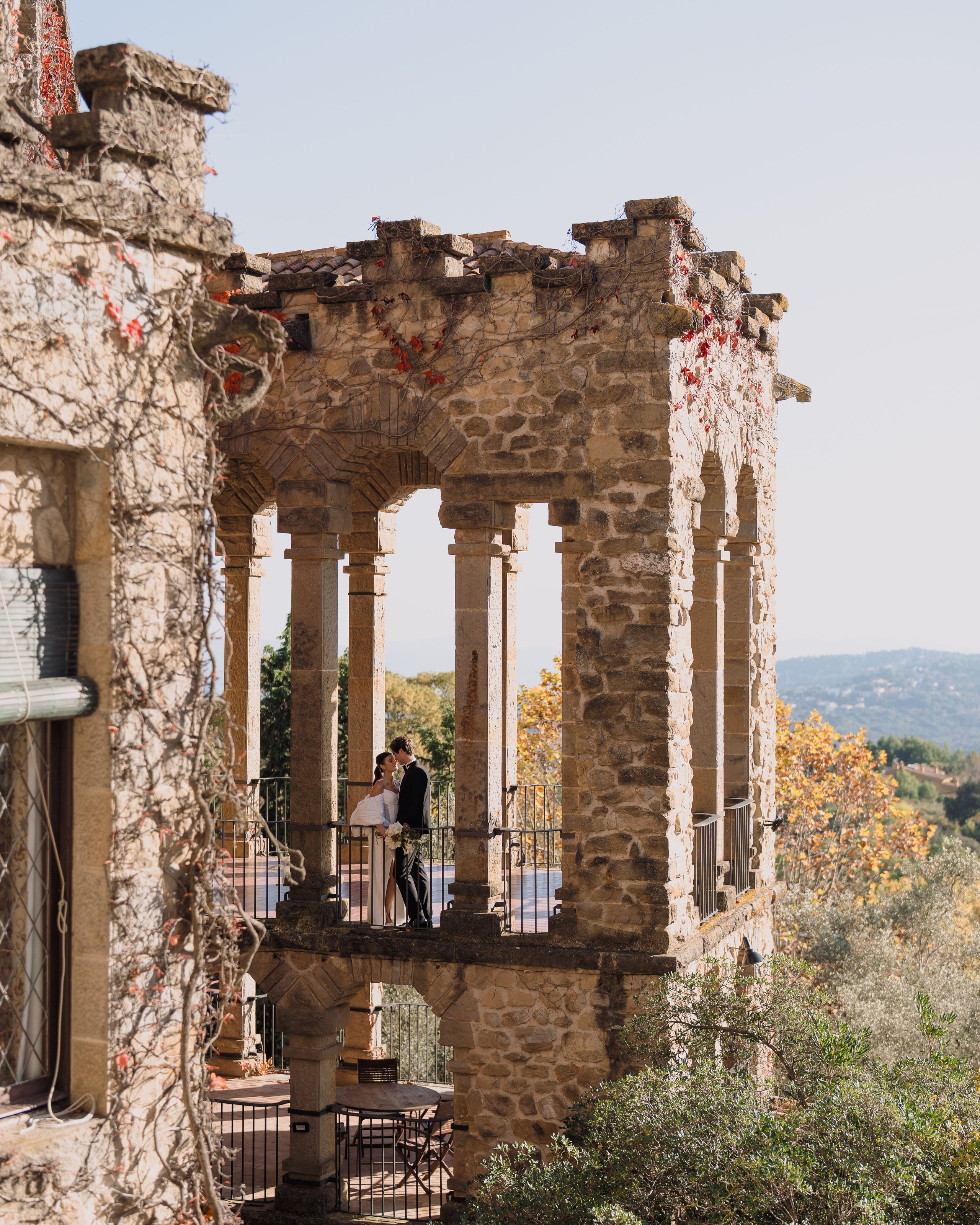 A couple framed by the arches of an old stone terrace.